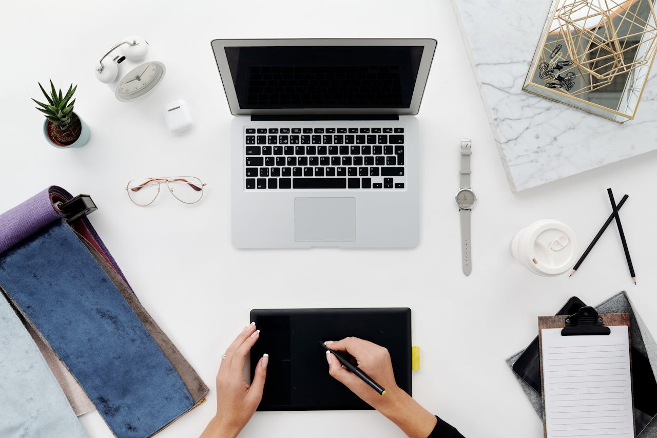 Top view of a modern home office setup with a laptop and drawing tablet, perfect for remote work and creative endeavors.